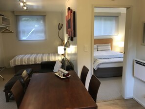 Une chambre d’hôtel avec une table à manger en bois, deux lits, un canapé et une lampe.