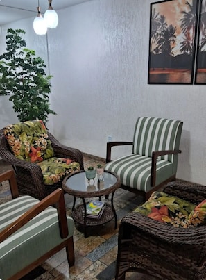 A room with wicker furniture, a round table, and a potted plant.