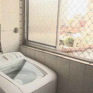 A laundry machine in a corner with a window.