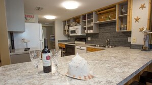 Une cuisine avec un plan de travail en marbre, une bouteille de vin et des verres.