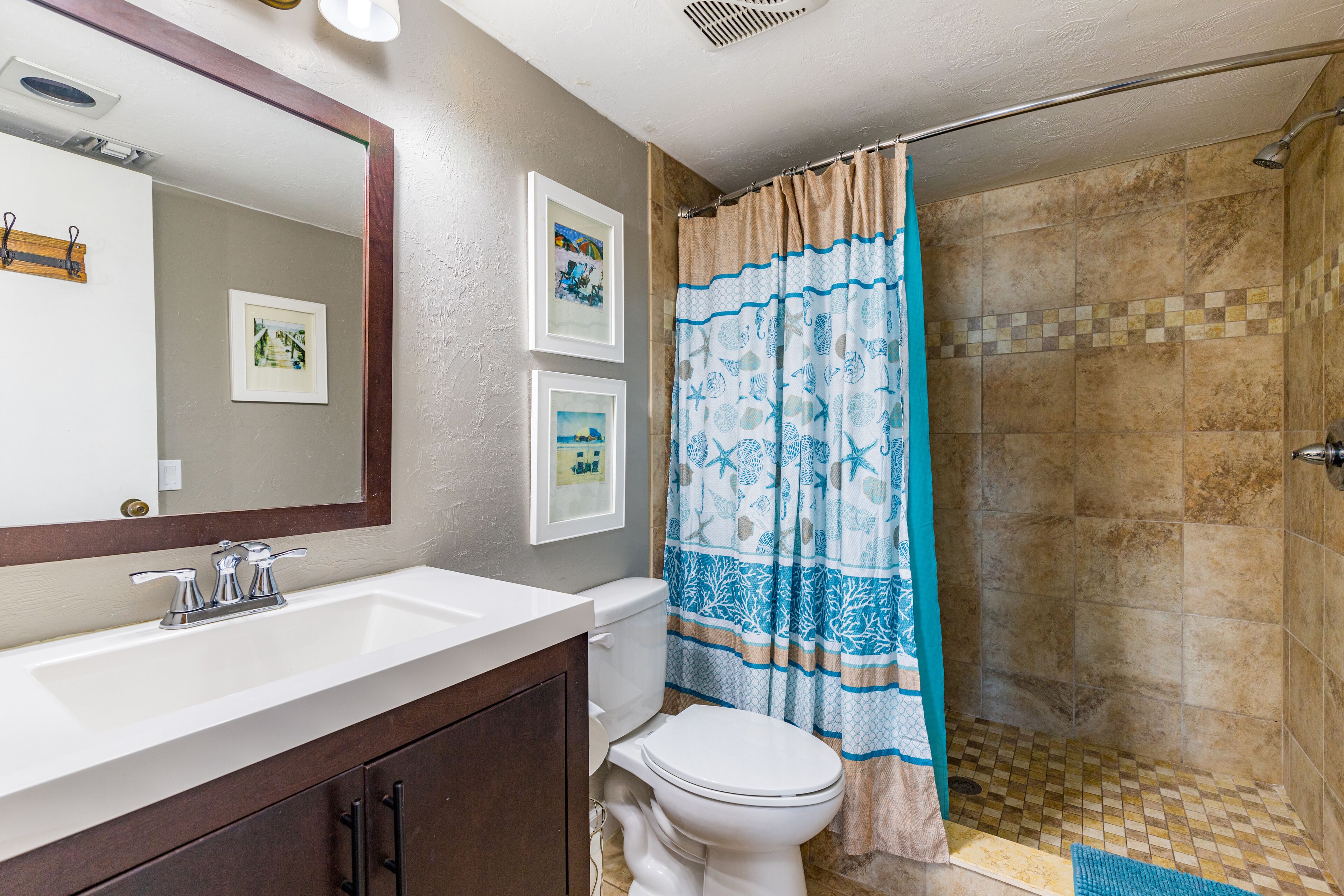 Une salle de bain avec un lavabo blanc, des toilettes et une douche avec un rideau à motifs.