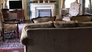 A living room with a fireplace, a sofa, a television, and a painting on the wall. - Loyd Hall Plantation (Cheneyville)