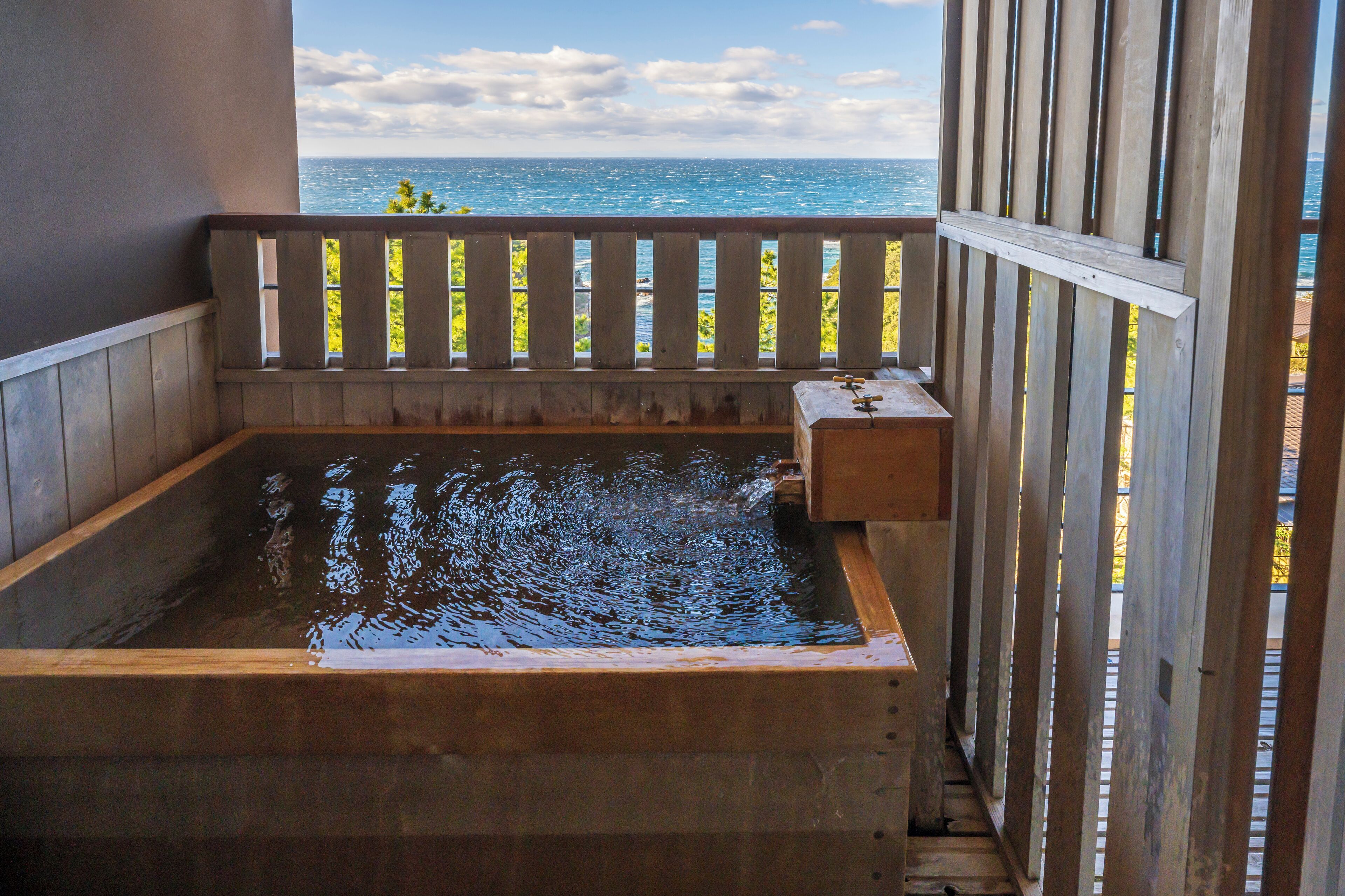 A wooden hot tub with a view of the ocean.