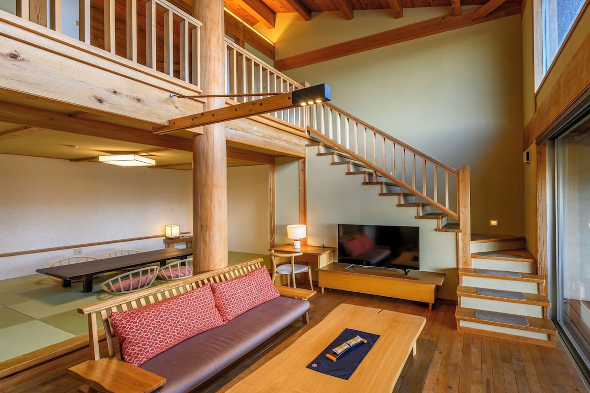 Een houten interieur met een trap, een bank, een televisie en een eethoek.