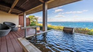 Een houten terras met een jacuzzi en rieten stoelen met uitzicht op een wateroppervlak.