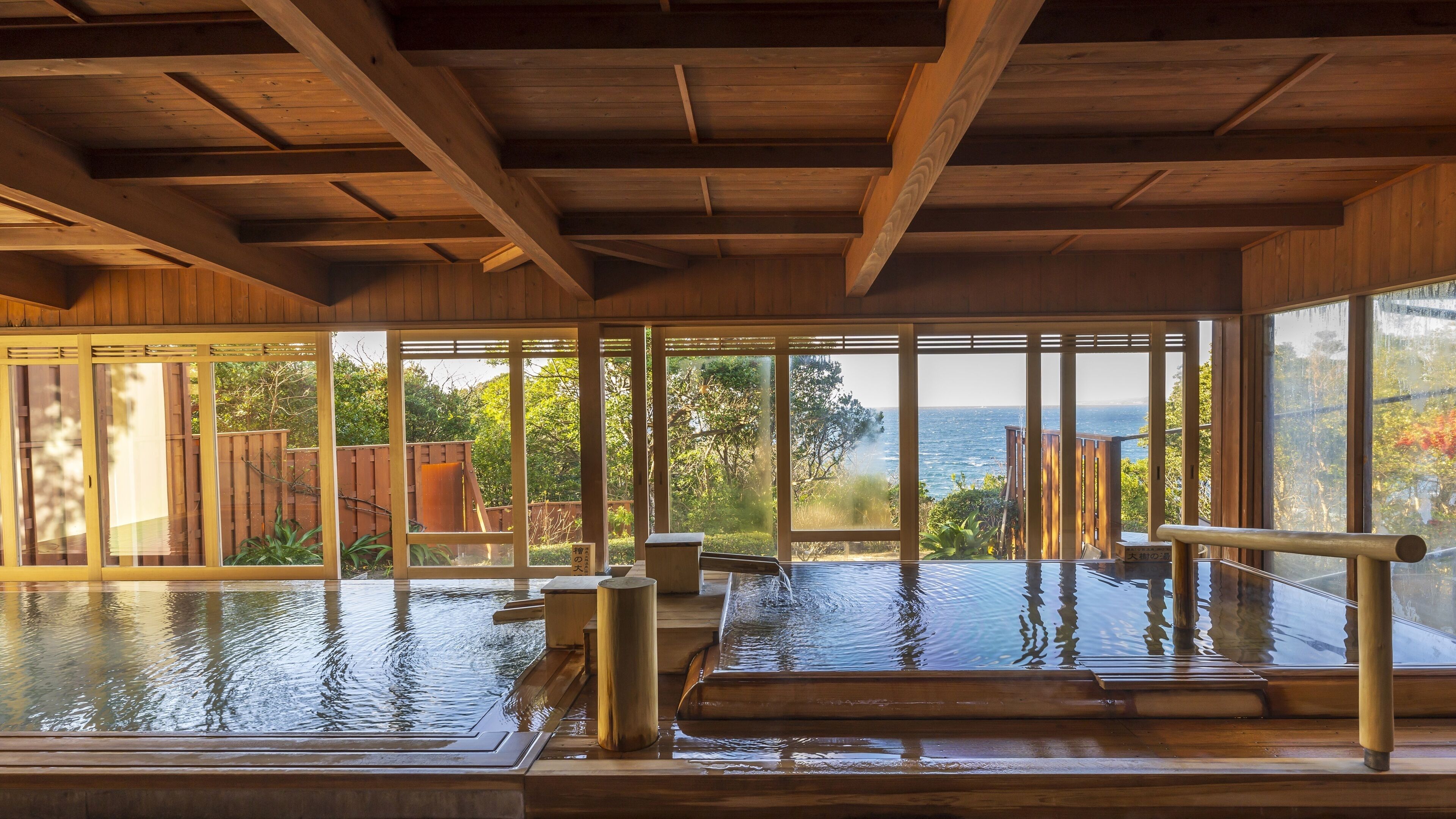 A wooden spa with large windows overlooking a body of water and a view of the sea.
