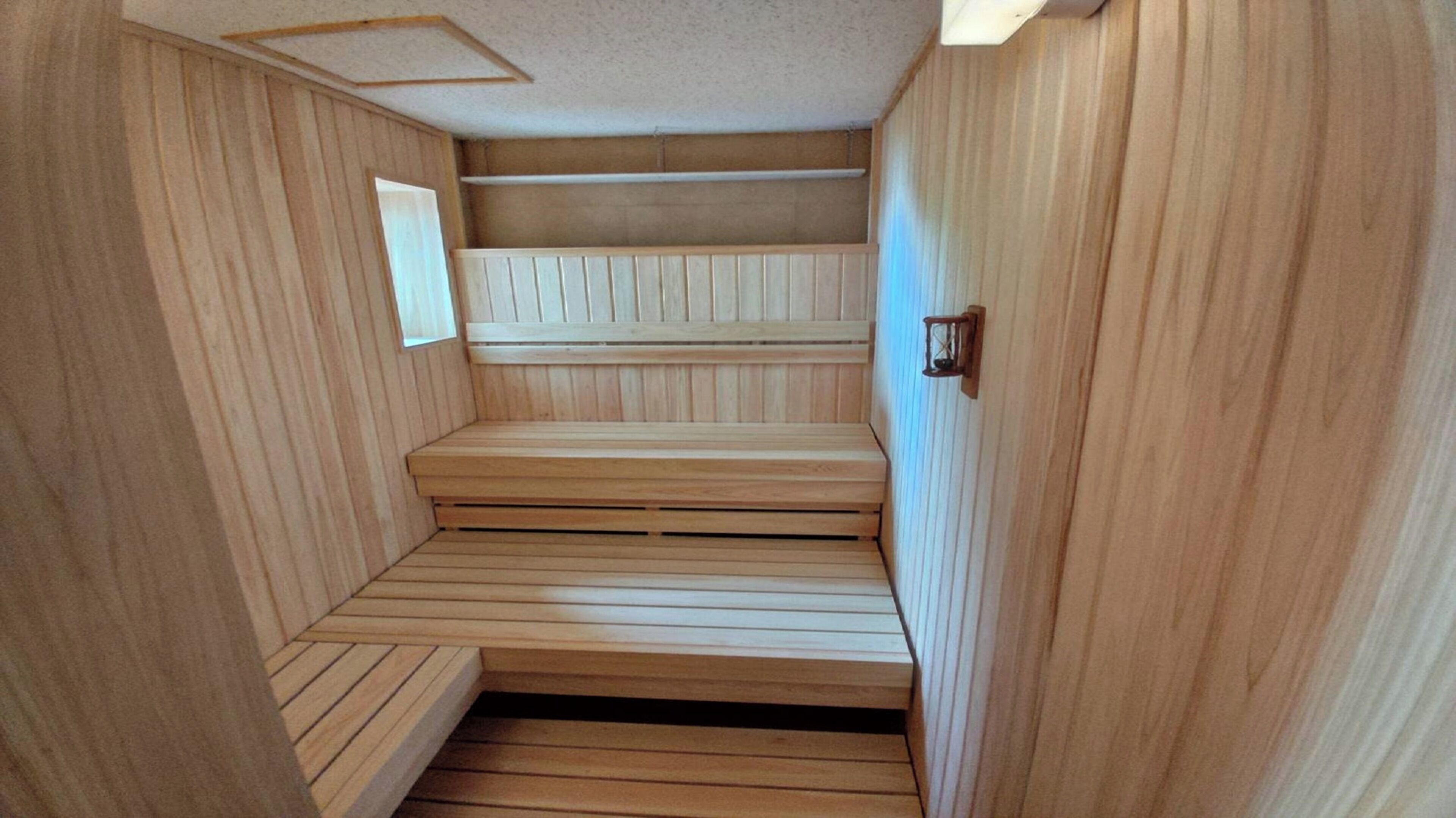 Un sauna avec des bancs en bois et un plancher incliné.