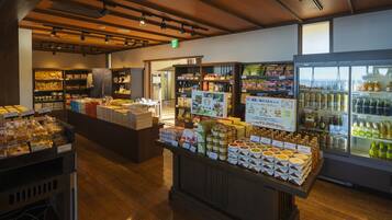 Een winkelinterieur met schappen vol diverse producten, een koelvitrine en een houten toonbank met verpakte goederen.