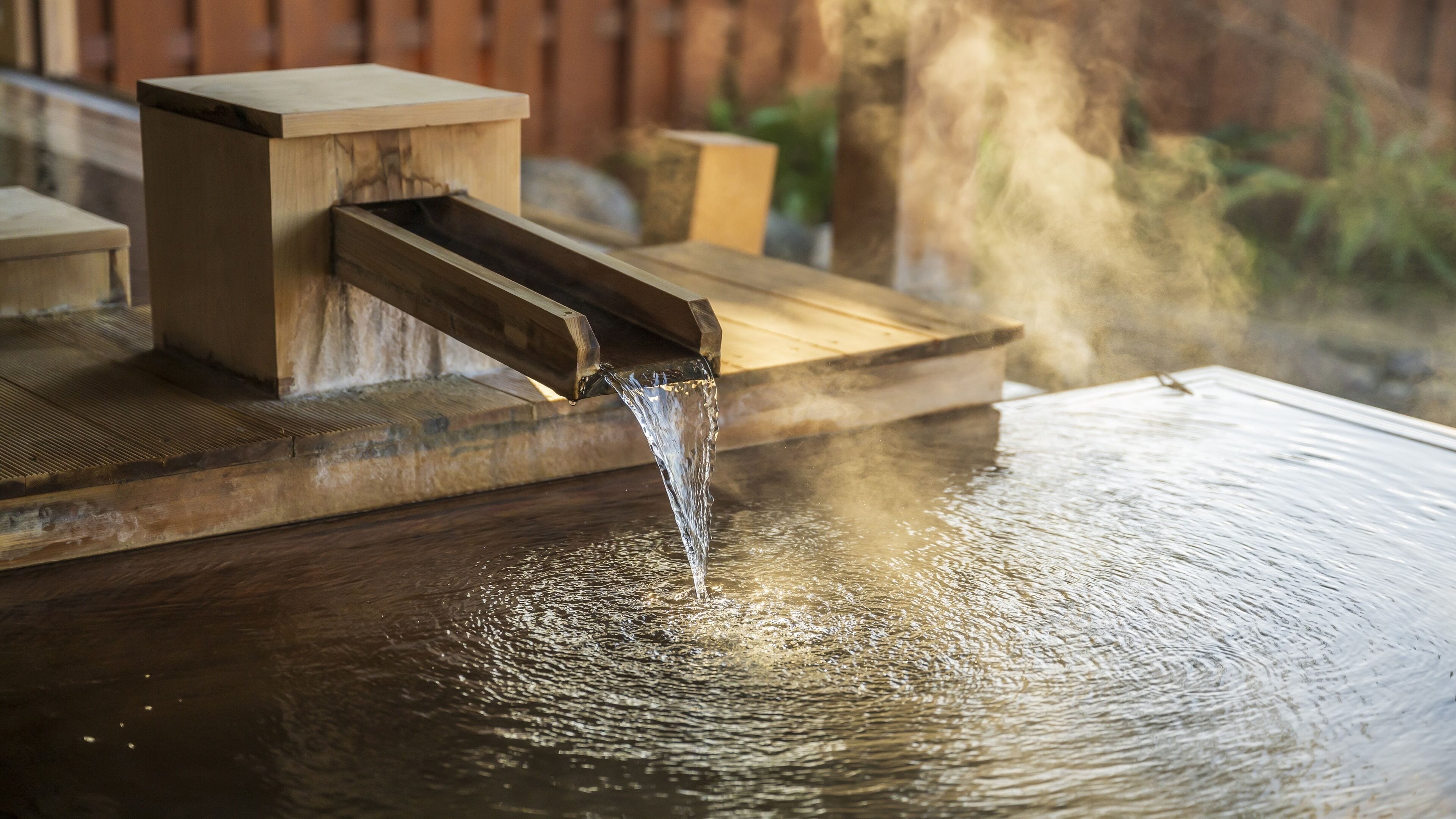 A wooden water feature with a stream flowing into a reflective pool.