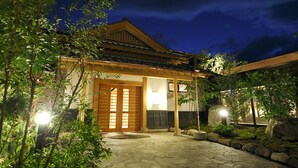 Een traditioneel Japans gebouw met een pannendak, houten deuren en een pad van stenen dat naar de ingang leidt.