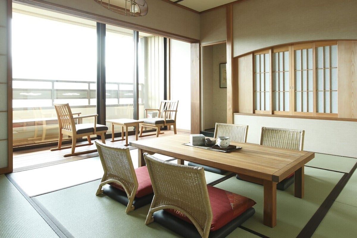 Une pièce de style japonais traditionnel, avec un sol recouvert de tatamis, une basse table en bois et des paravents en papier de riz (shoji).