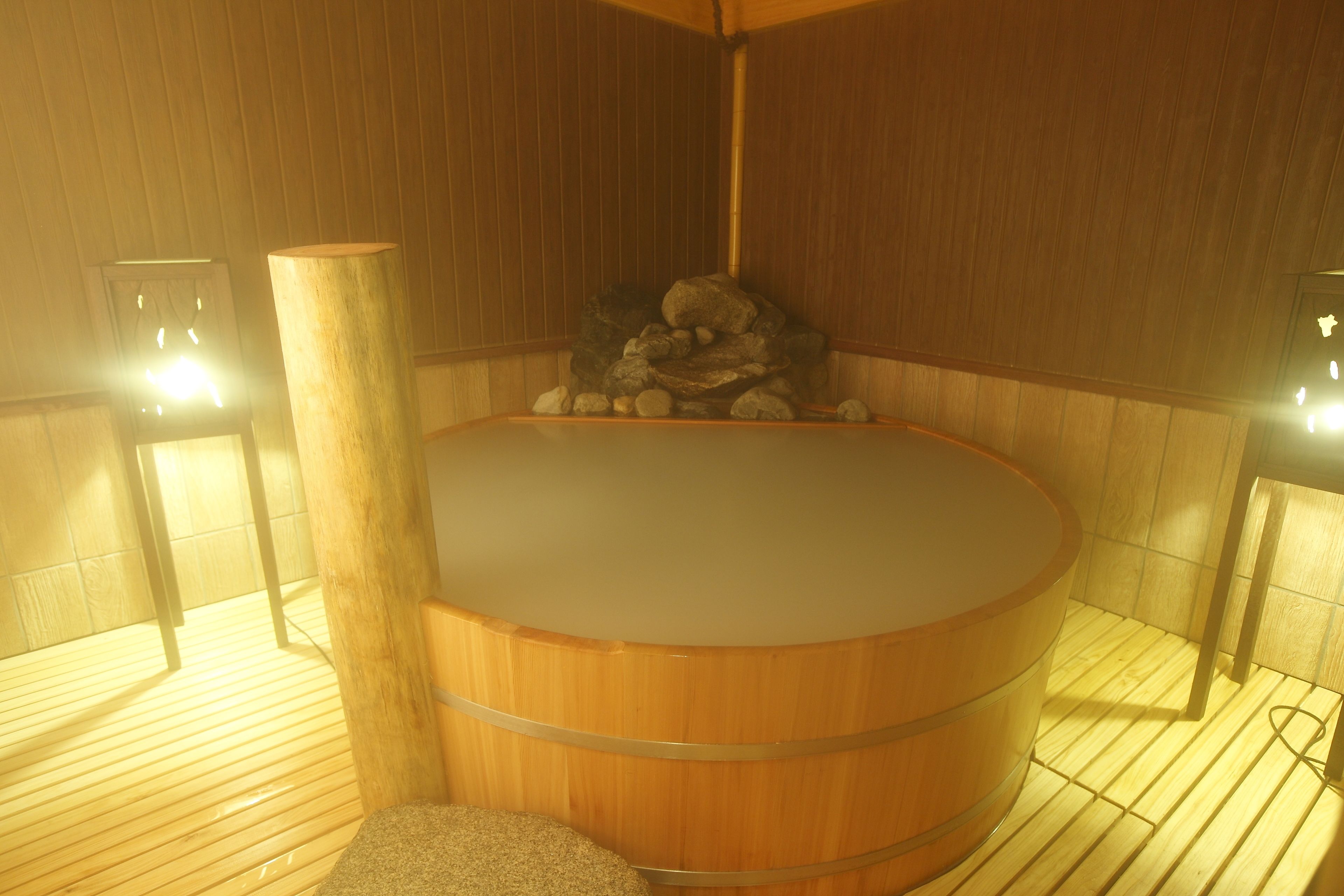 A wooden sauna with a stone bench and a wooden pillar.