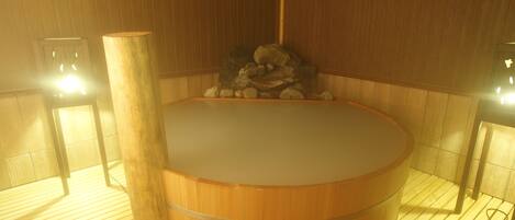 A wooden sauna with a stone bench and a wooden pillar.
