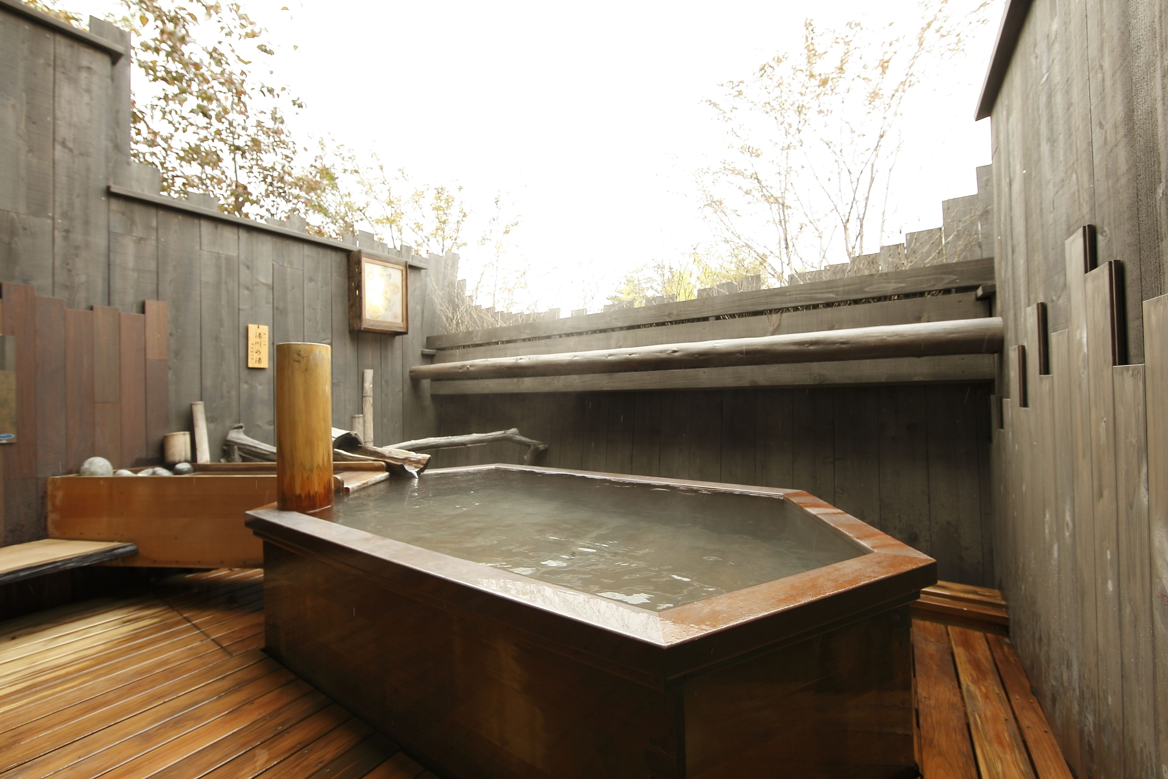 A hot tub area with a wooden deck, a wooden wall, and a wooden fence.