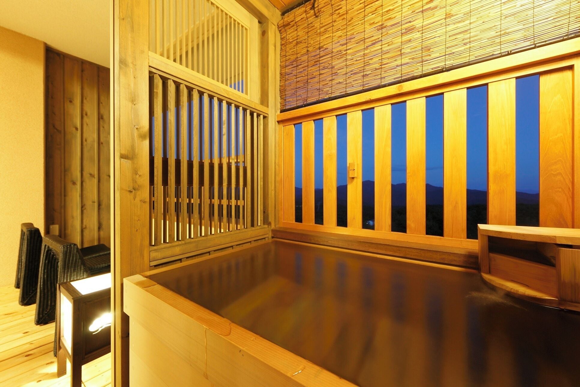 A traditional Japanese onsen with wooden railings and a view of mountains.