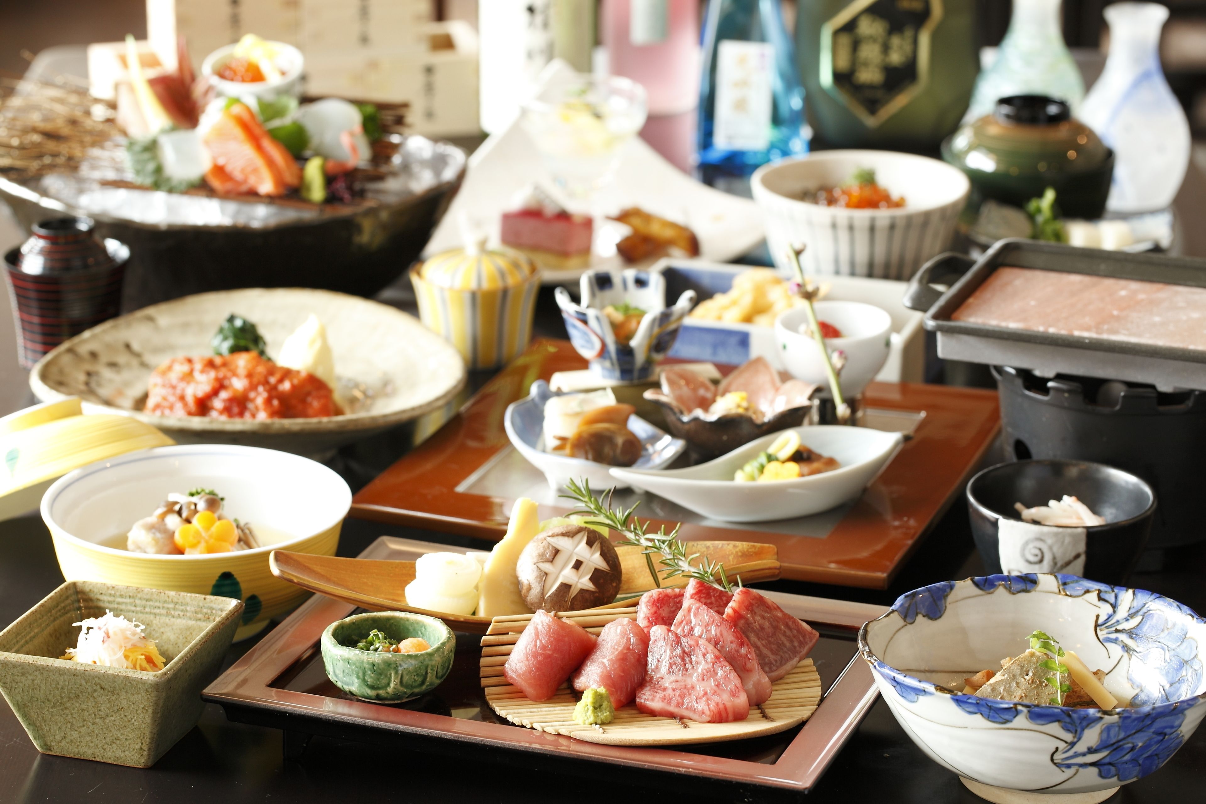 A variety of dishes on a table, including sushi, sashimi, and other Japanese cuisine.
