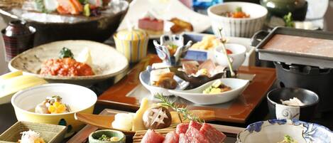A variety of dishes on a table, including sushi, sashimi, and other Japanese cuisine.