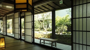 Een traditionele Japanse kamer met tatami vloerbedekking, schuifdeuren en uitzicht op een tuin.