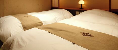 A hotel room with two beds, a nightstand with a lamp, and a wall with a decorative panel.