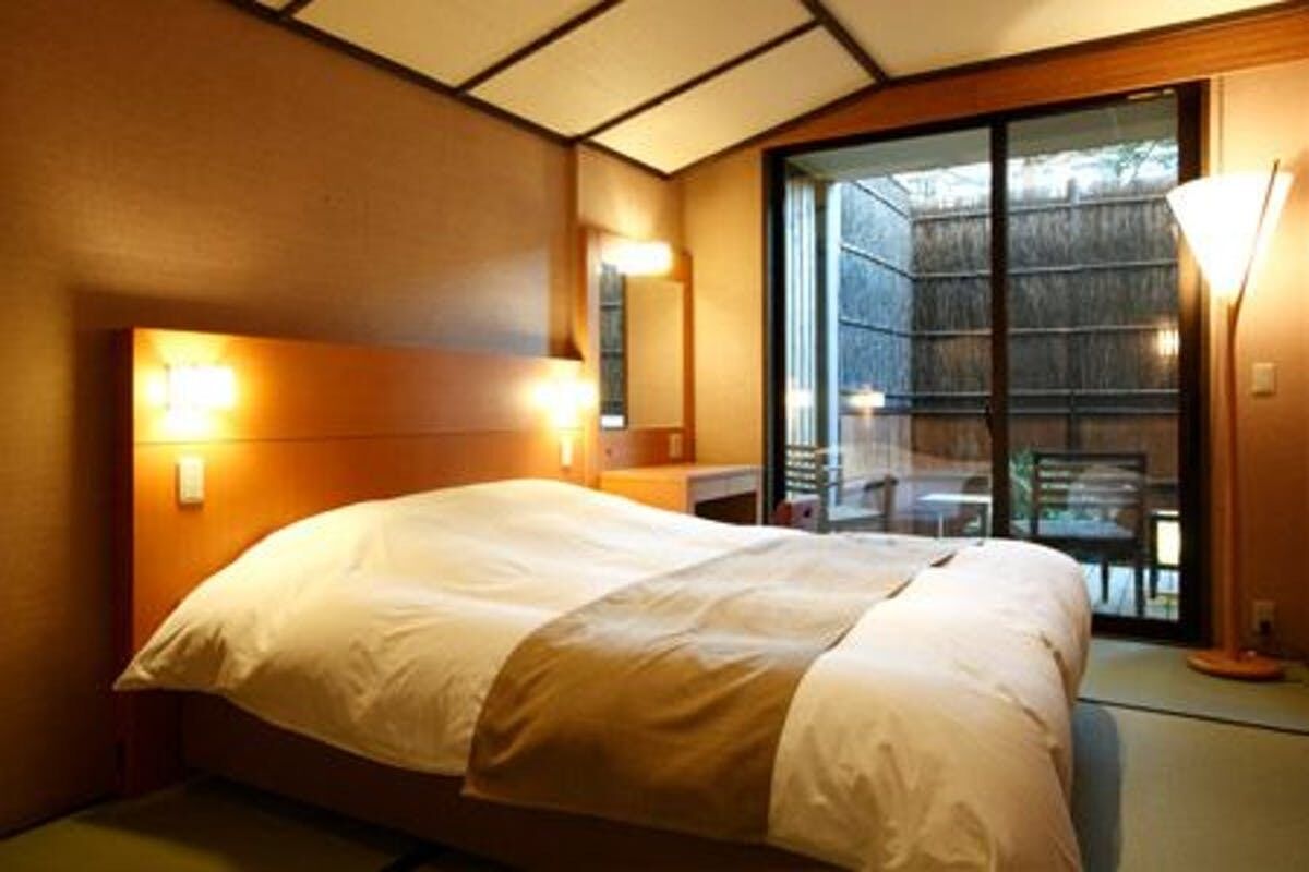 Une chambre d’hôtel avec un lit, une table de chevet, une lampe et une grande fenêtre.