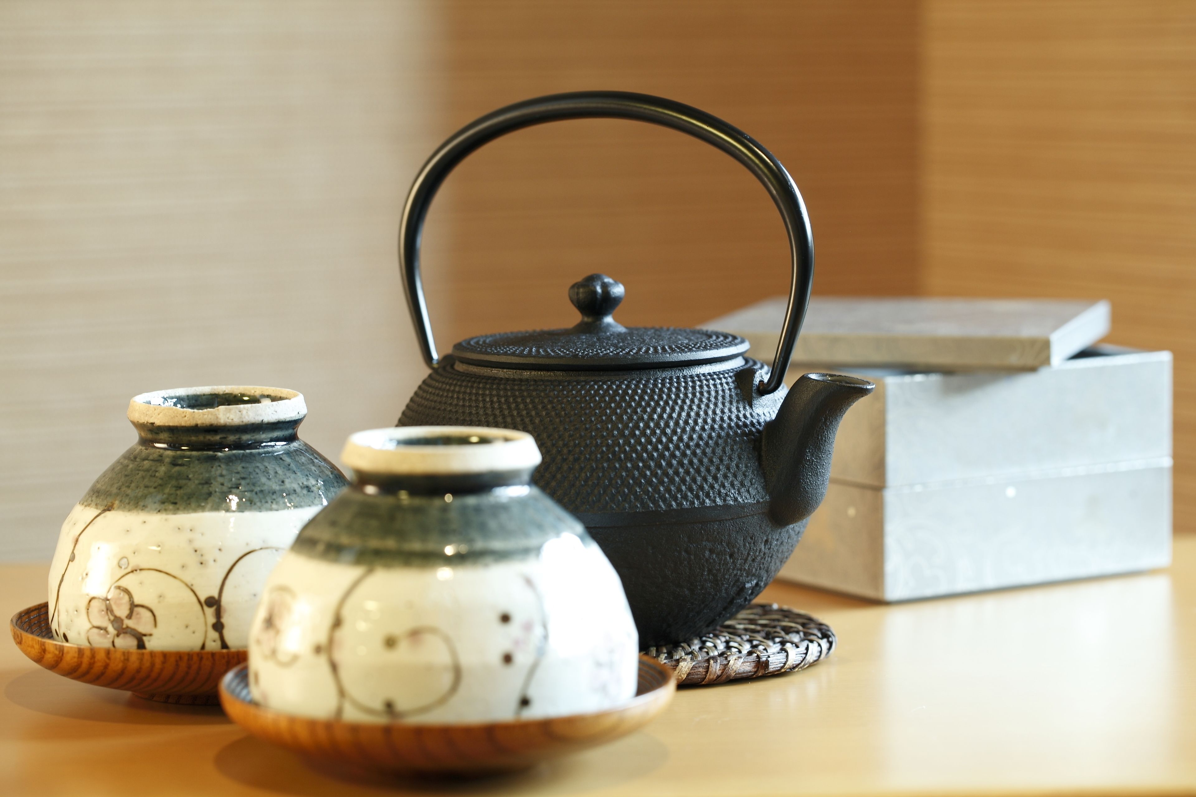 A tea set with a black teapot and two ceramic cups on a wooden table.