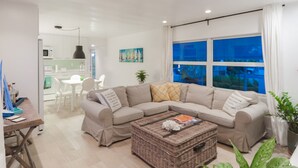A modern living room with a sectional sofa, a coffee table, and a dining area in the background. - Beautiful Waterfront Villa (Tavernier)