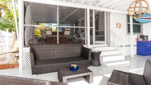 A covered outdoor seating area with wicker furniture, a coffee table, and a blue bowl. - Beautiful Waterfront Villa (Tavernier)