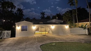 A white building with a gated entrance, a small window, and a heart-shaped light fixture. - 3Bd. & 2Bth. Private Island Security Gated Villa Miami Beach (North Bay Village)