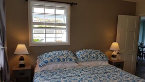 Un dormitorio con cama, dos lámparas de noche, una ventana y una puerta.