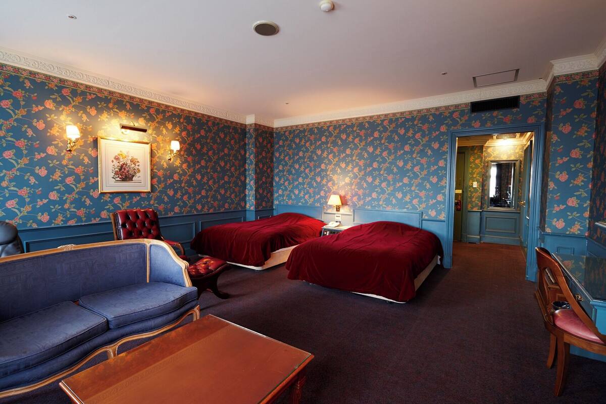 A hotel room with two beds, a sofa, a table, and a chair.