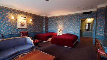 Habitación de hotel con dos camas, un sofá, una mesa y una silla.