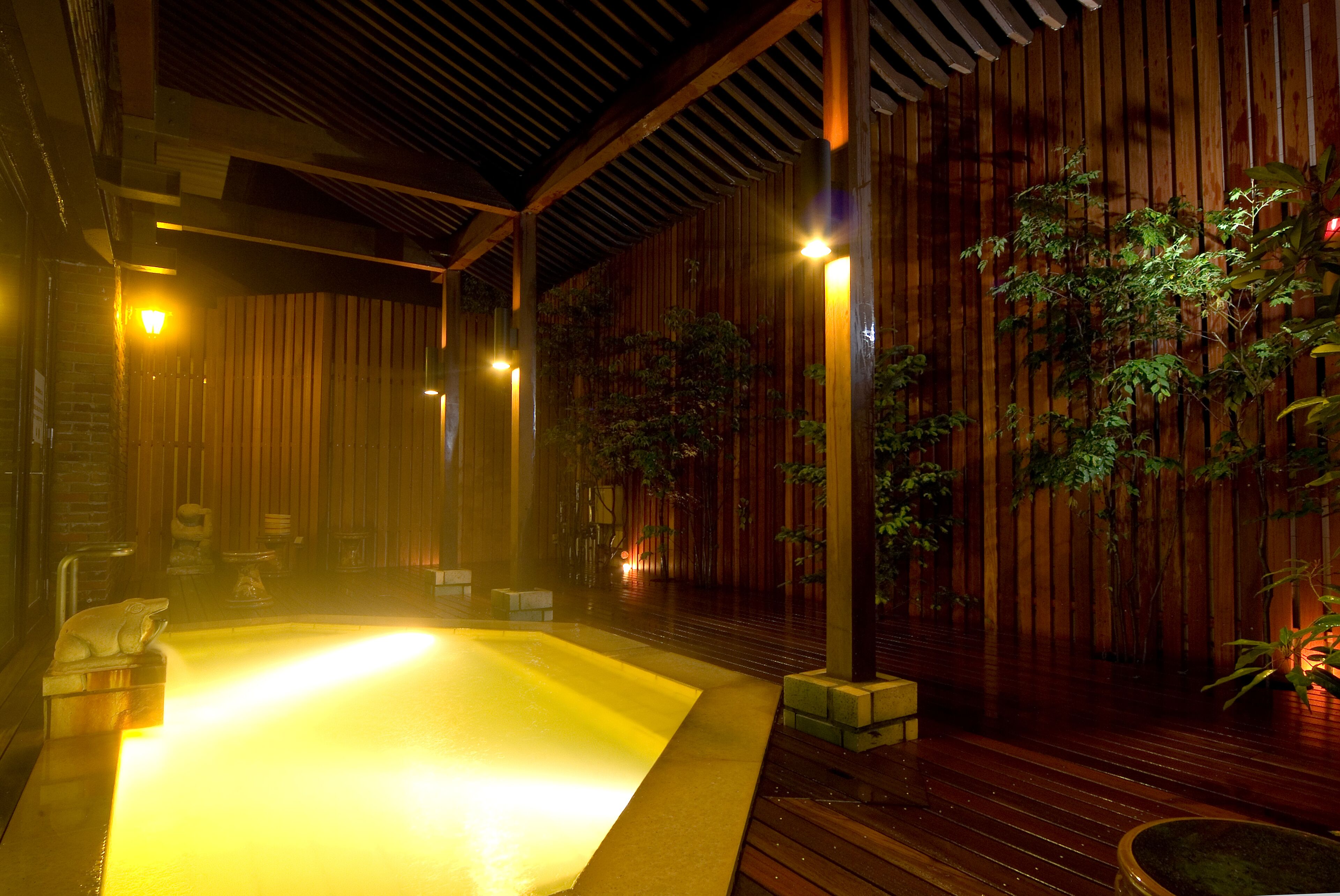 A hot tub area with wooden walls and a tiled floor, surrounded by potted plants.