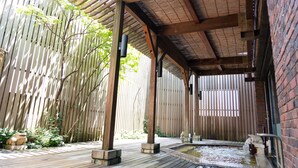 A wooden deck with a hot tub, bamboo fence, and a brick wall. - Wellness Forest NASU (Nasu)