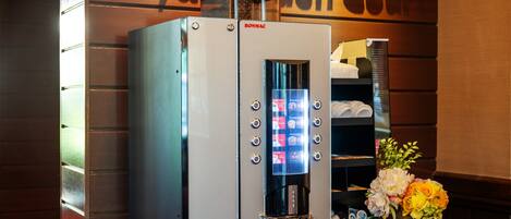 Eine Kaffeemaschine mit digitalem Display und Tasten steht auf einer Holzauslage in der Hotelhalle.