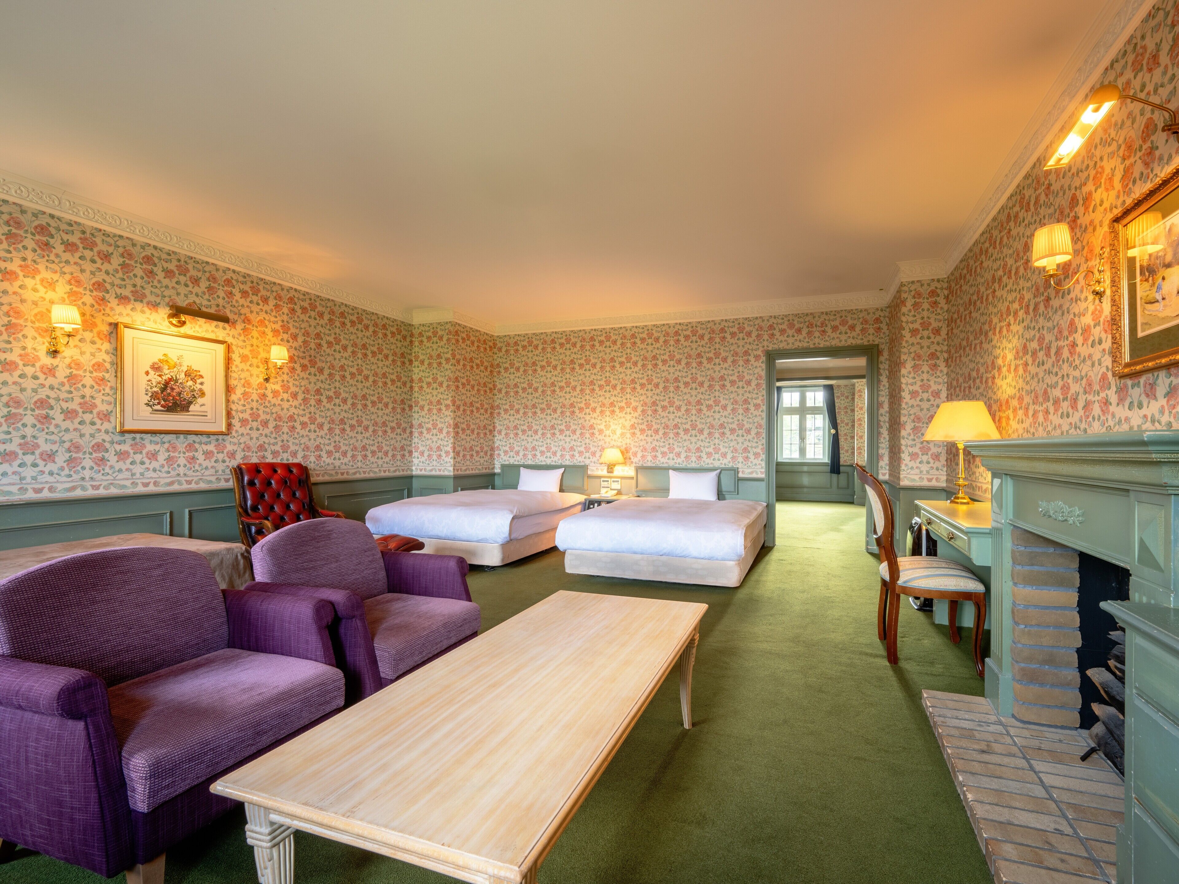 Una habitación de hotel con dos camas, un sofá, una mesa y una chimenea.