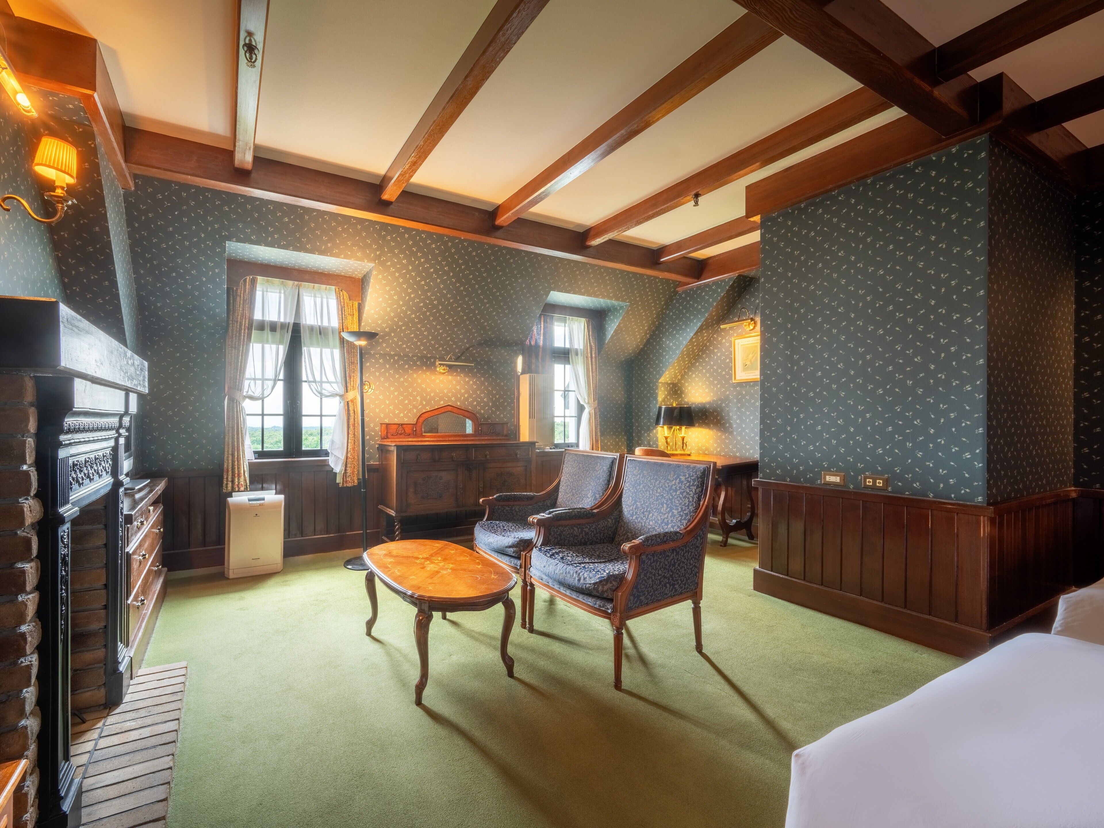 A room with a fireplace, two armchairs, a small table, and a wooden bench.