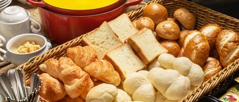 A breakfast setting with bread, croissants, and a pot of soup.