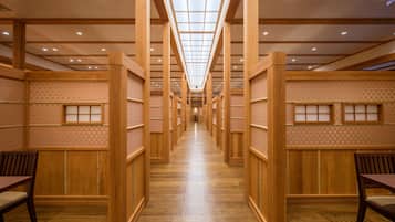 A corridor with wooden paneling and a checkered wall pattern, leading to a central area with a ceiling light fixture.