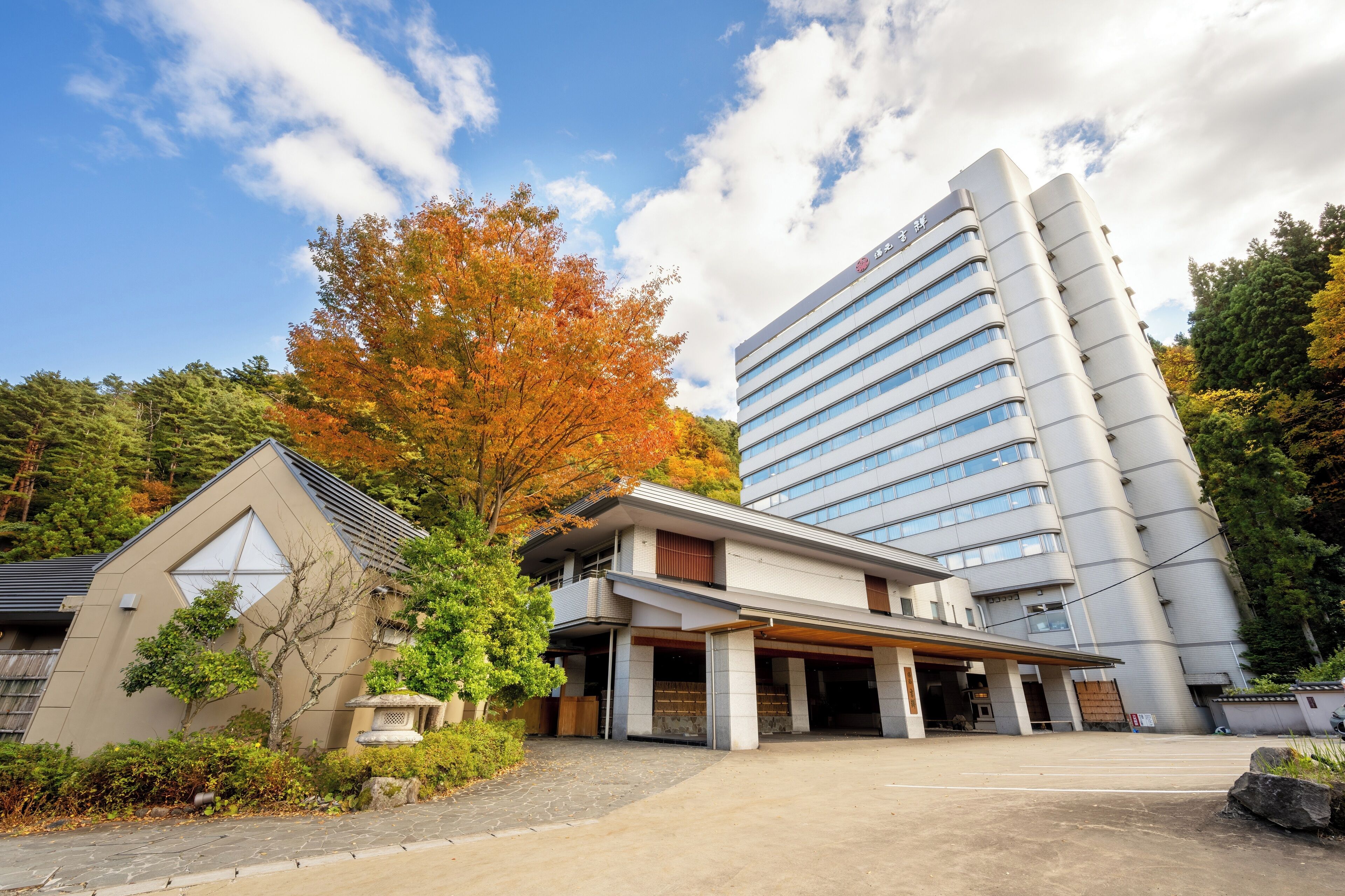 A modern hotel with a large glass facade, a covered entrance, and a parking area.