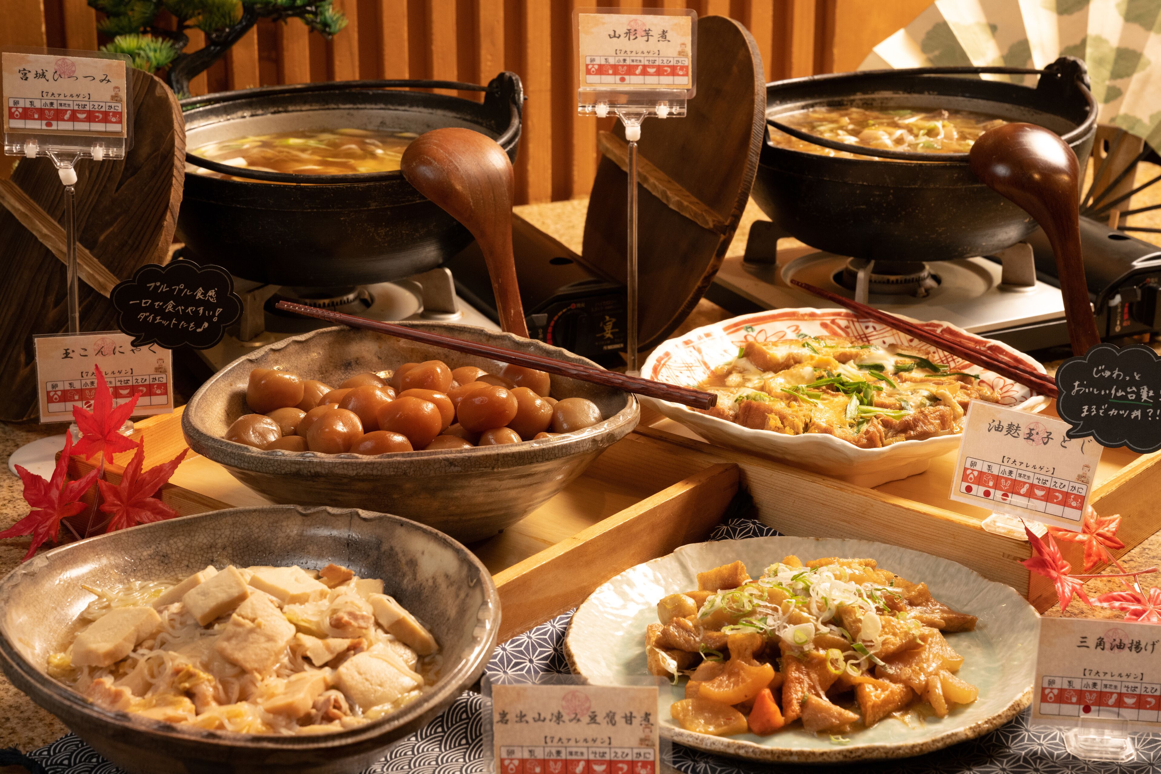 A variety of traditional Japanese dishes displayed on a wooden table with multiple bowls and plates of food, accompanied by chopsticks and a teapot.