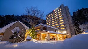 Hotel com design moderno, apresentando uma construção grande com vários andares e um anexo menor com telhado inclinado.