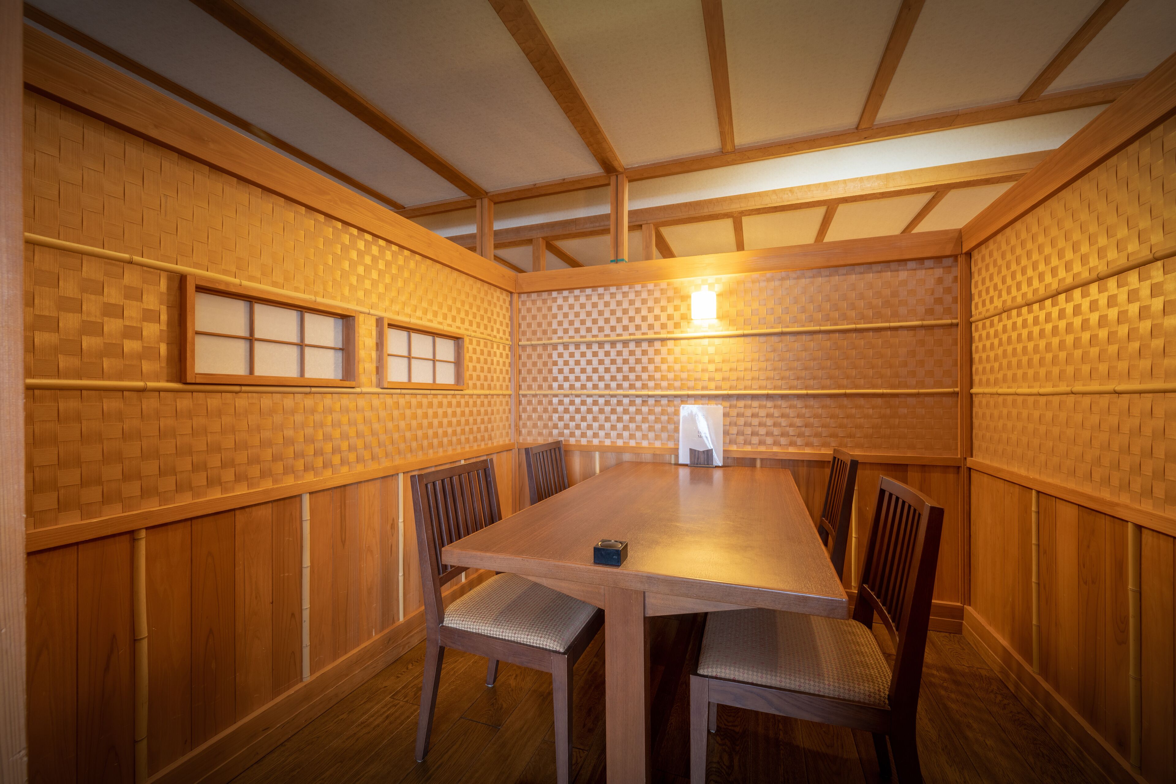 Una habitación con una mesa de comedor de madera, seis sillas y un estampado de cuadros en la pared.