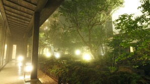 A covered wooden walkway with a view of a garden area, including trees and a rock garden. - Oyado Konoha (Kusatsu)