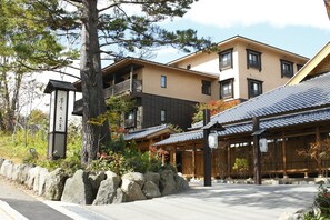 Traditional Japanese-style building with a covered entrance and stone pathway, surrounded by natural beauty.