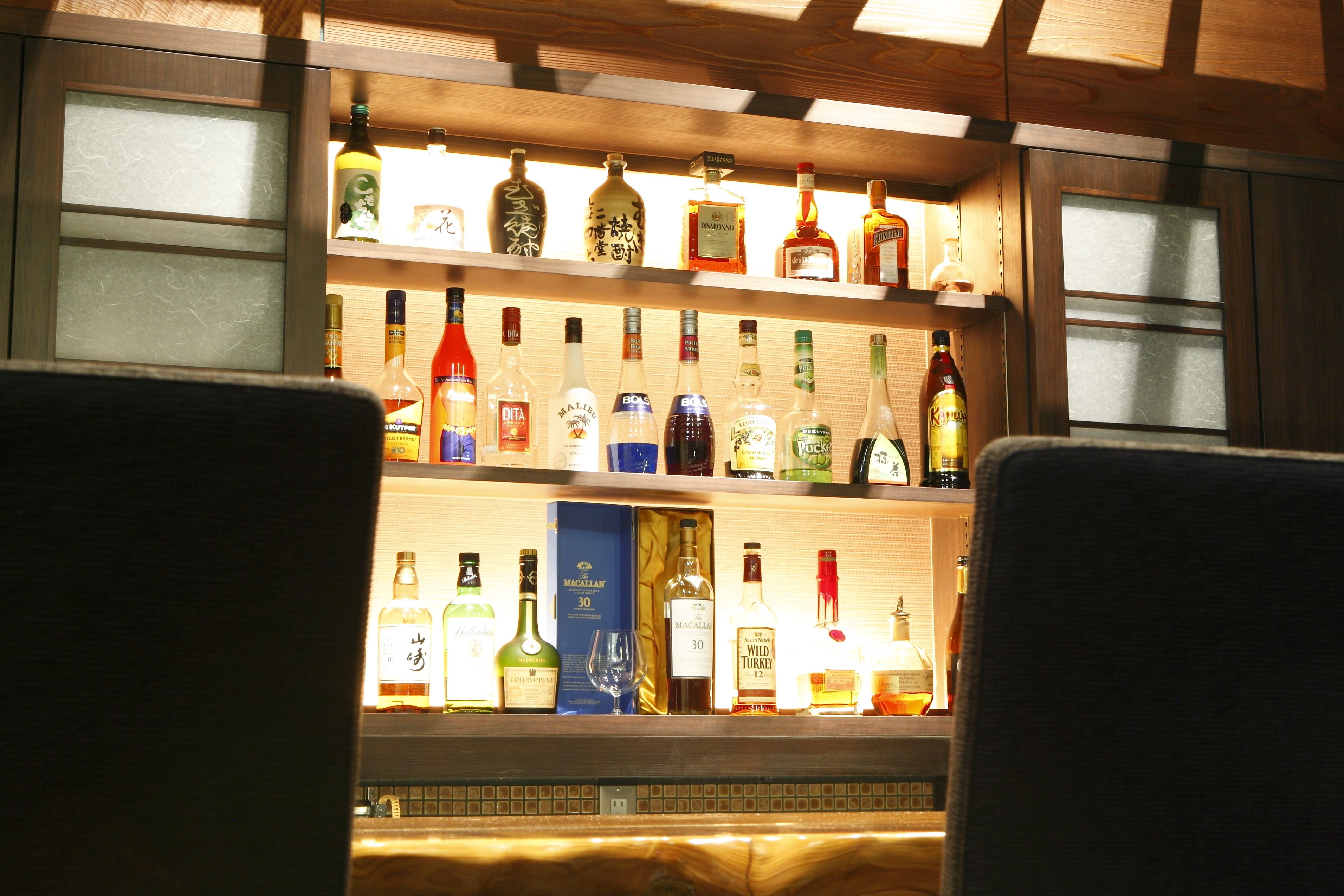 A bar area with shelves of various liquor bottles.