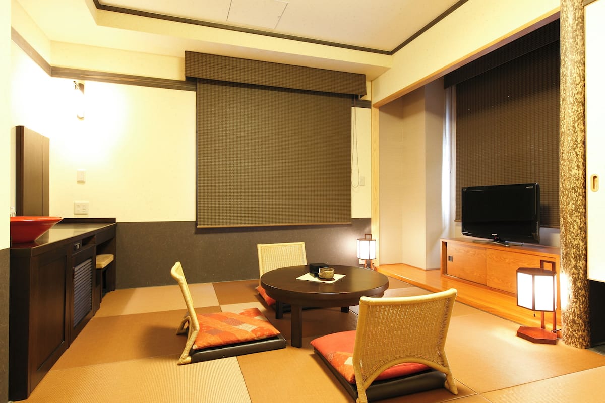 A traditional Japanese-style room with tatami flooring, a low table, and cushions.