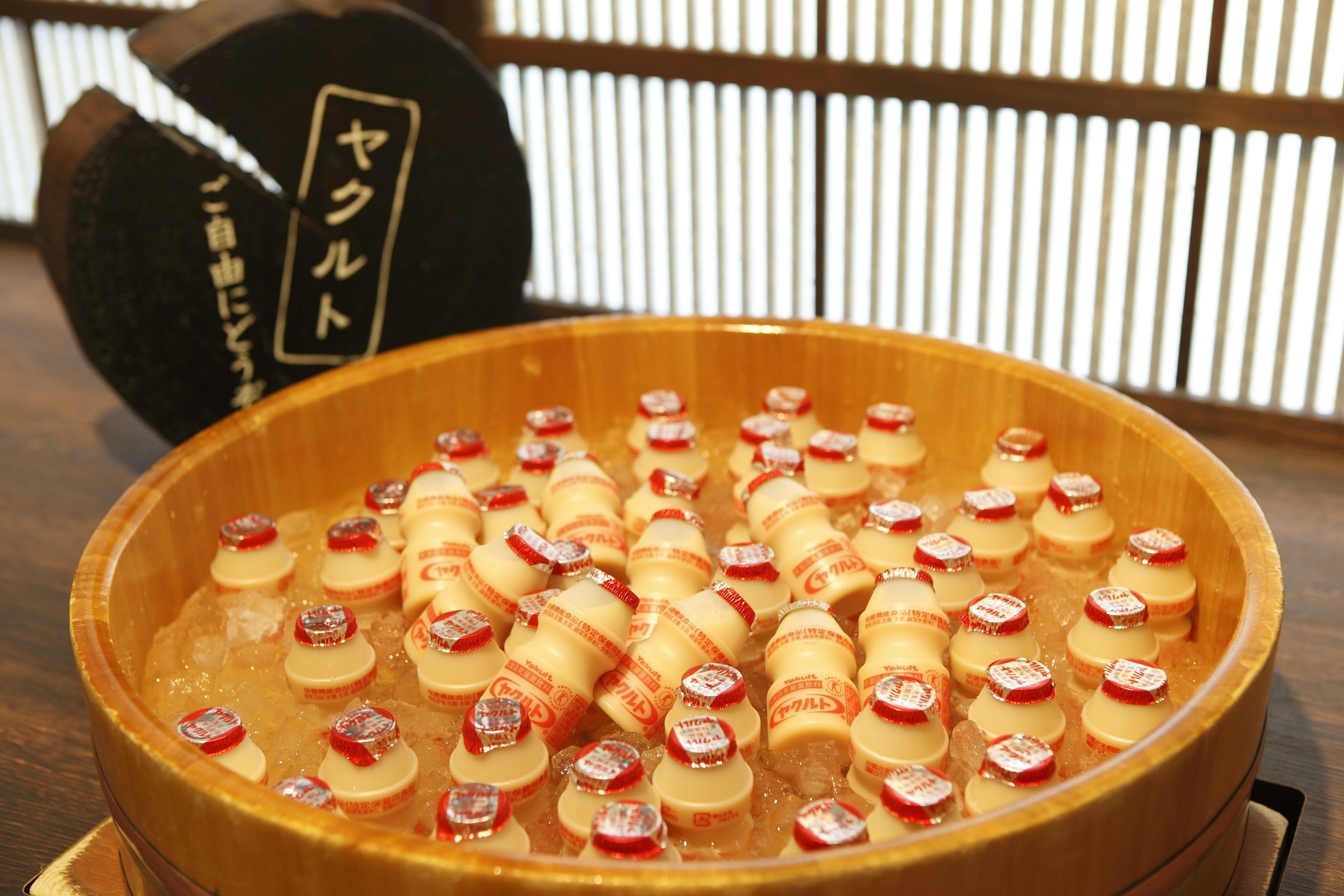 A wooden bowl filled with bottles of sake, placed on a wooden table.