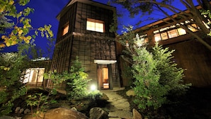 A modern building with a stone pathway leading to the entrance, surrounded by greenery and rocks. - Oyado Konoha (Kusatsu)