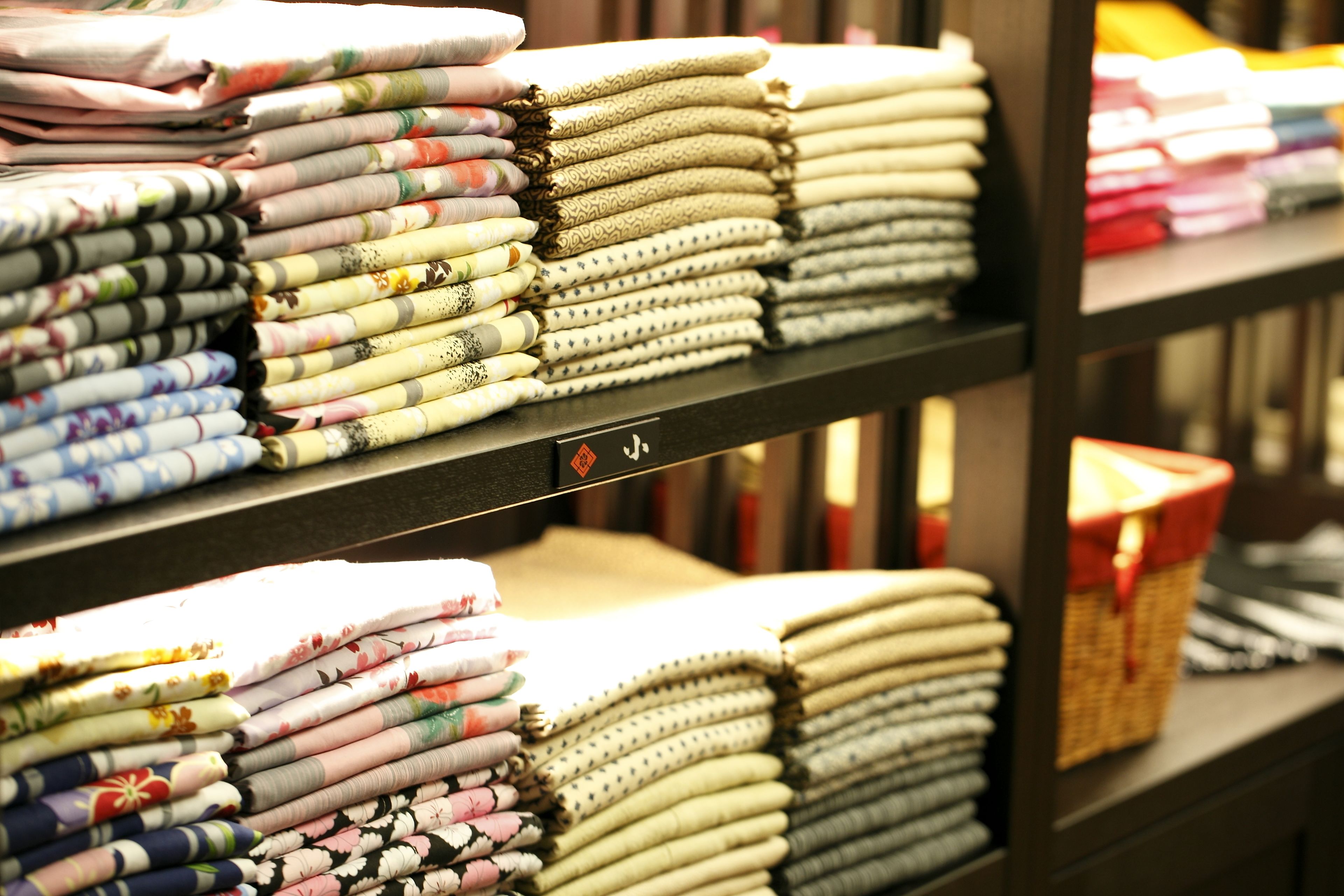 Neatly stacked fabric rolls on shelves in a store.