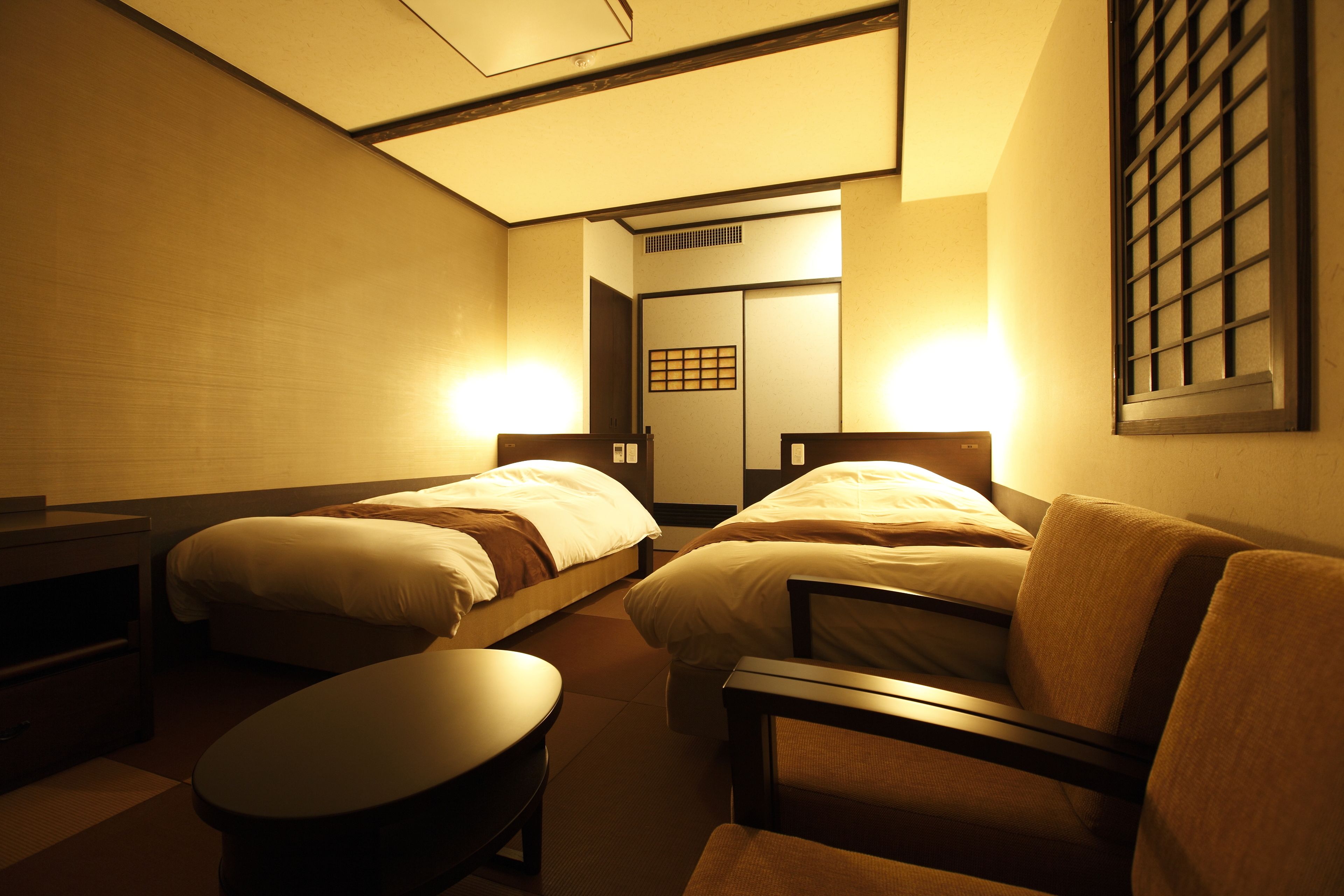 Habitación de hotel con dos camas, una mesita y una silla.